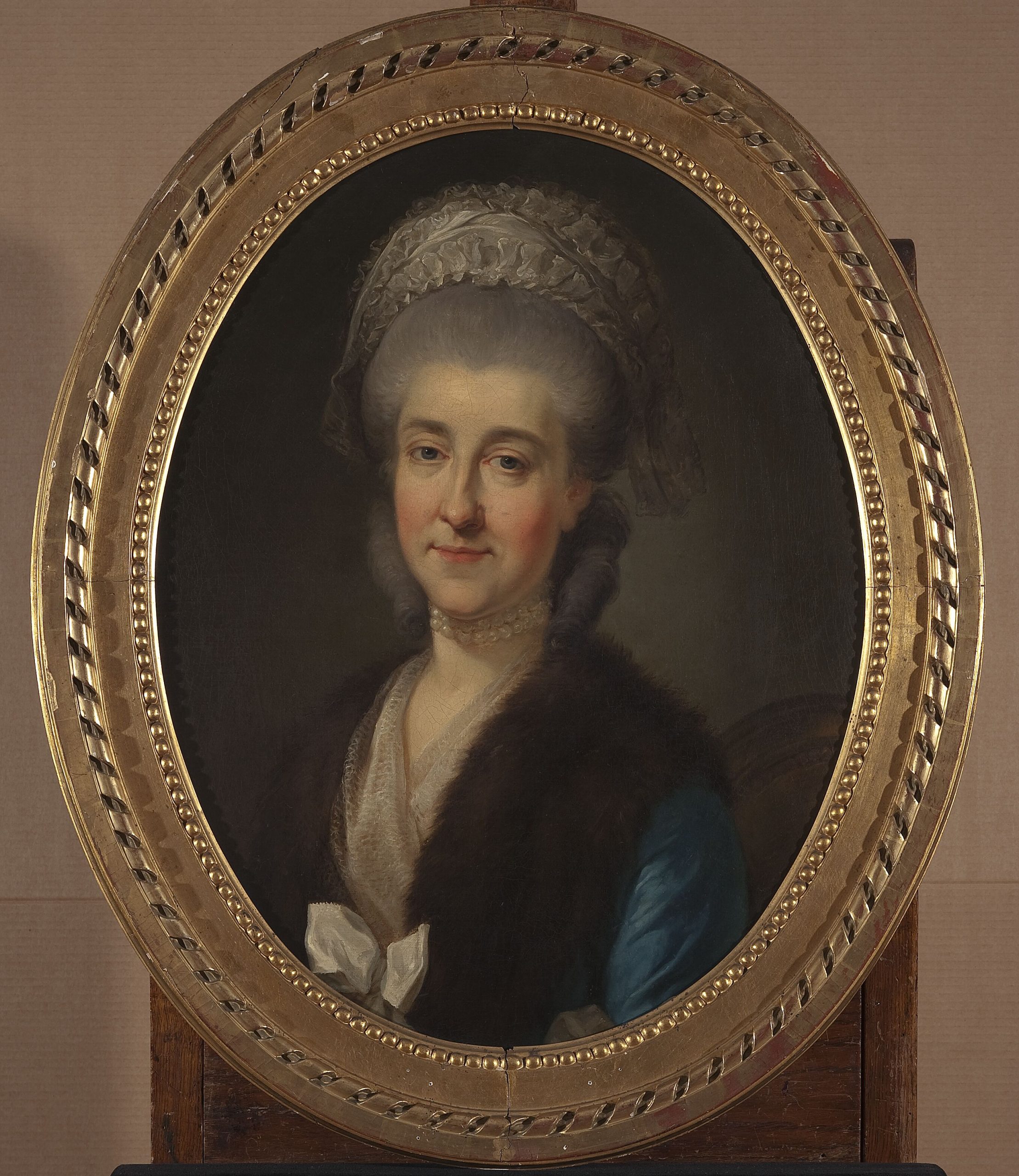 Portret kobiety w złotej, dekoracyjnej ramie.